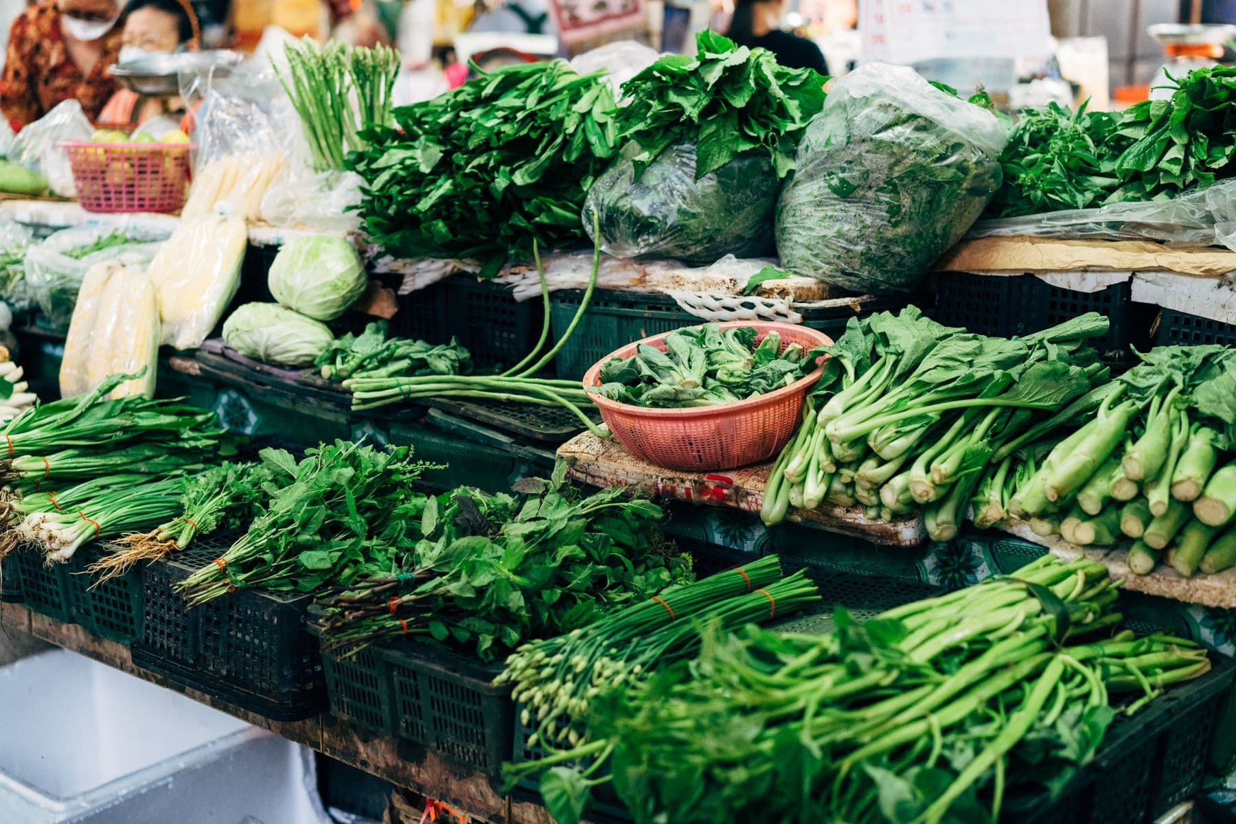 Leafy greens stacked in crates at an East African market stall