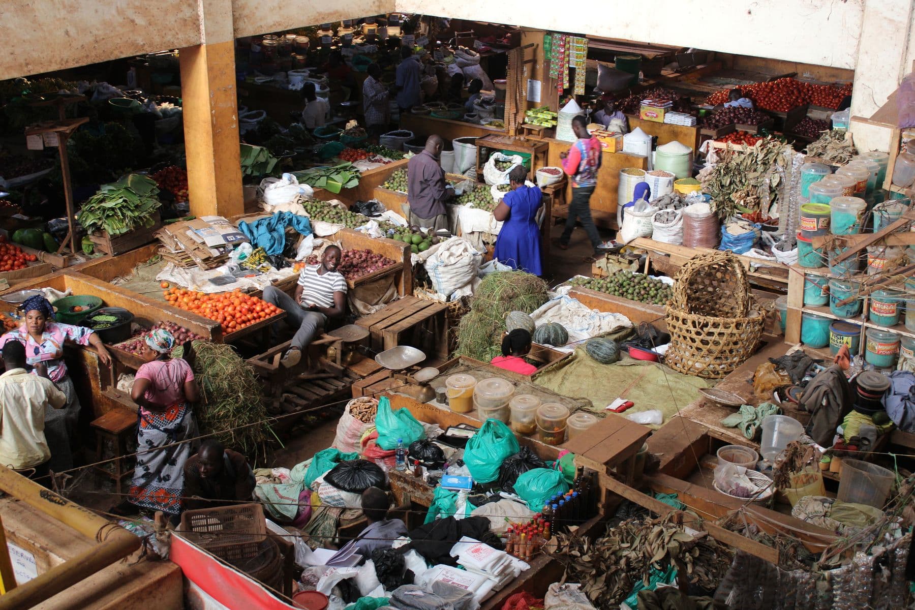A busy East African produce market with vendors and stalls